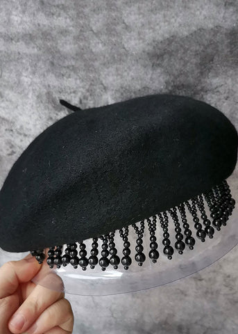 Modische schwarze Baskenmütze aus Wolle mit Nagelperlen und Quasten